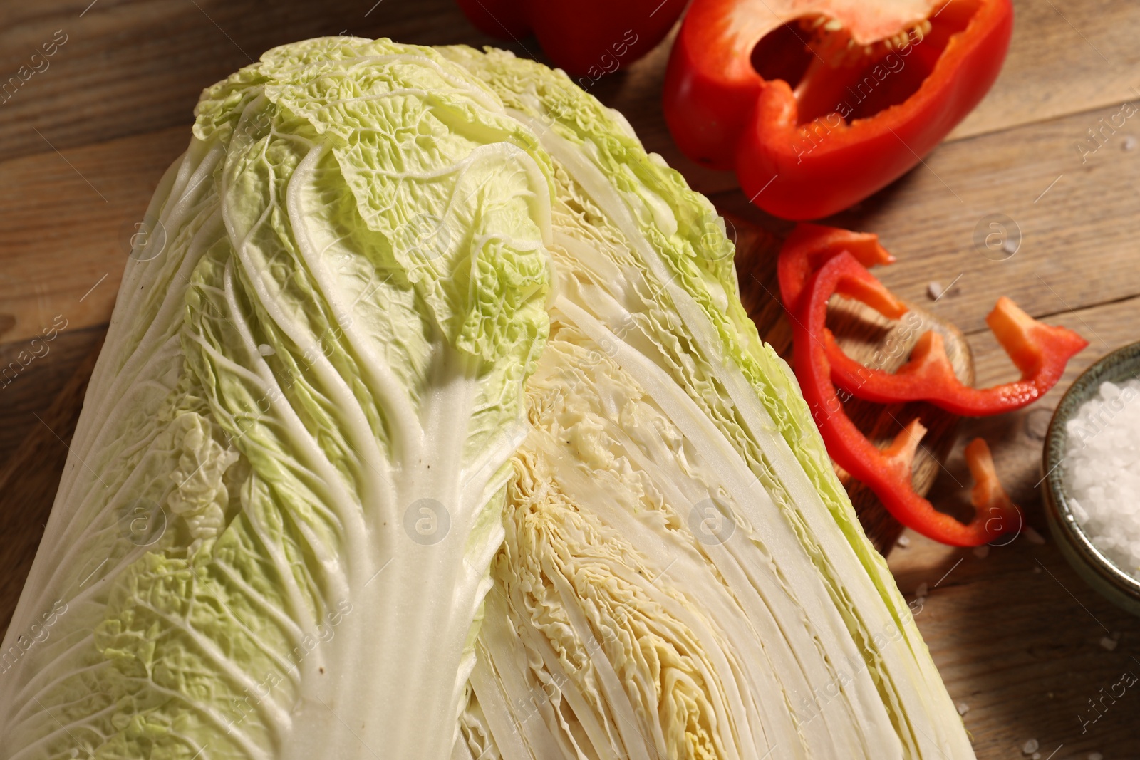 Photo of Fresh Chinese cabbages, bell peppers and salt on wooden table, closeup