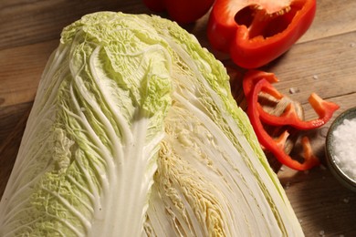 Photo of Fresh Chinese cabbages, bell peppers and salt on wooden table, closeup