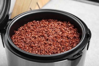 Photo of Modern multi cooker with boiled brown rice in kitchen, closeup