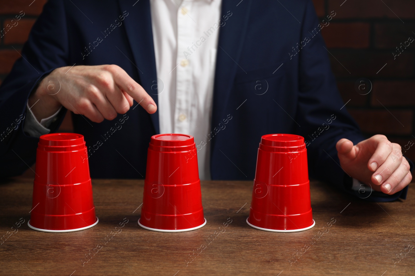 Photo of Man playing shell game at wooden table, closeup