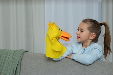 Cute little girl performing puppet show at home