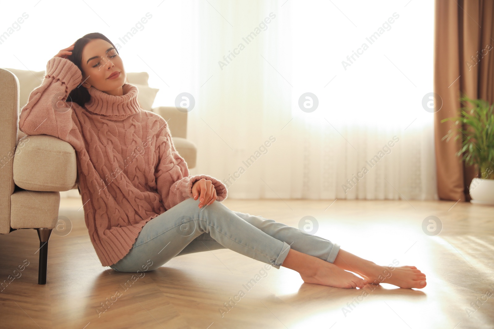 Photo of Woman sitting on warm floor in living room. Heating system