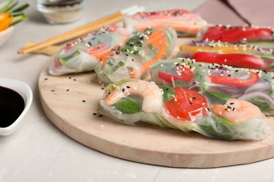 Delicious rolls wrapped in rice paper served on light table, closeup