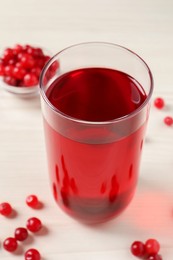 Photo of Tasty cranberry juice in glass and fresh berries on white wooden table, closeup