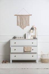 Stylish room interior with chest of drawers near white wall