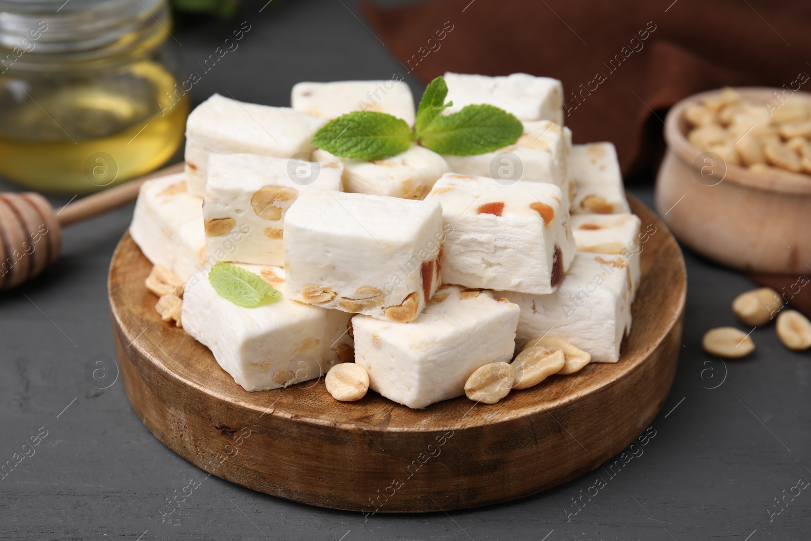 Photo of Pieces of delicious nutty nougat on wooden board, closeup