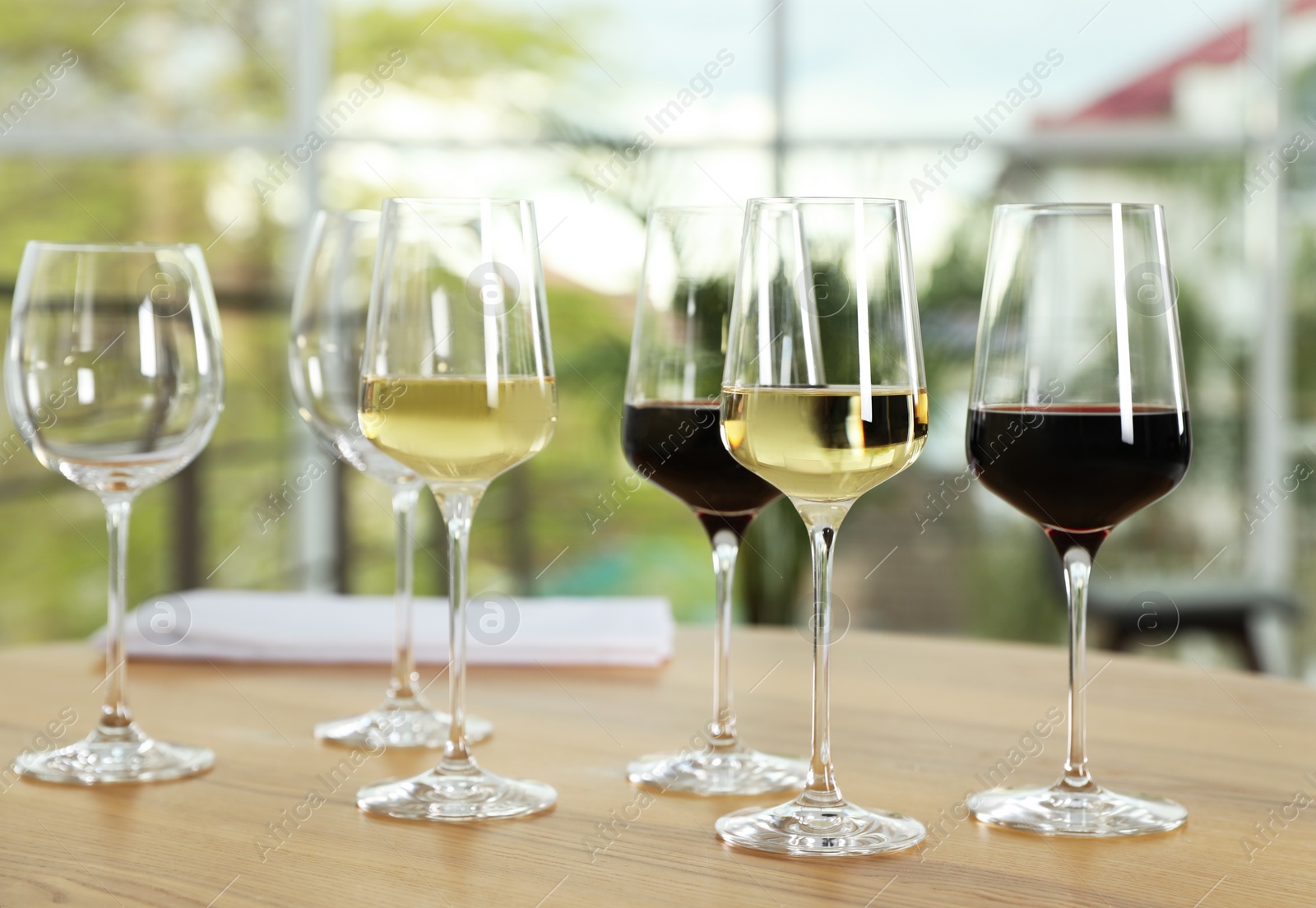 Photo of Glasses with different wines on table against blurred background