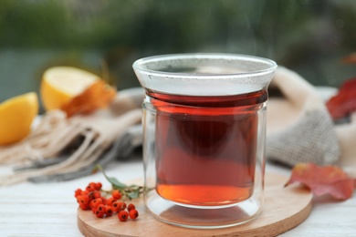 Photo of Cup of hot drink and scarf on window sill indoors. Cozy autumn atmosphere