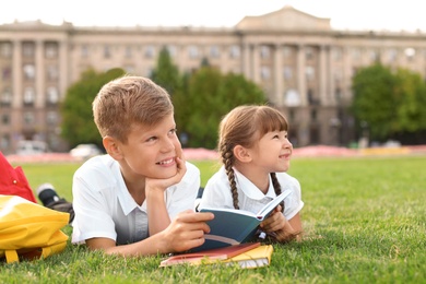 Children with stationery doing school assignment on grass outdoors