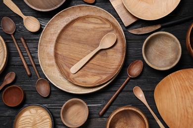 Photo of Flat lay composition with wooden dishware on black table