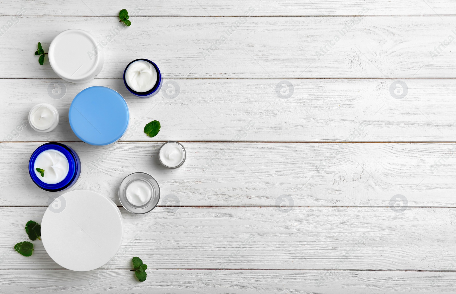 Photo of Jars with body cream on wooden background