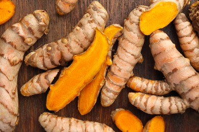 Photo of Many fresh turmeric roots on wooden table, flat lay