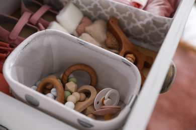 Photo of Modern open chest of drawers with baby clothes and accessories, closeup