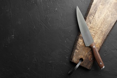 Photo of One sharp knife and board on dark textured table, top view. Space for text