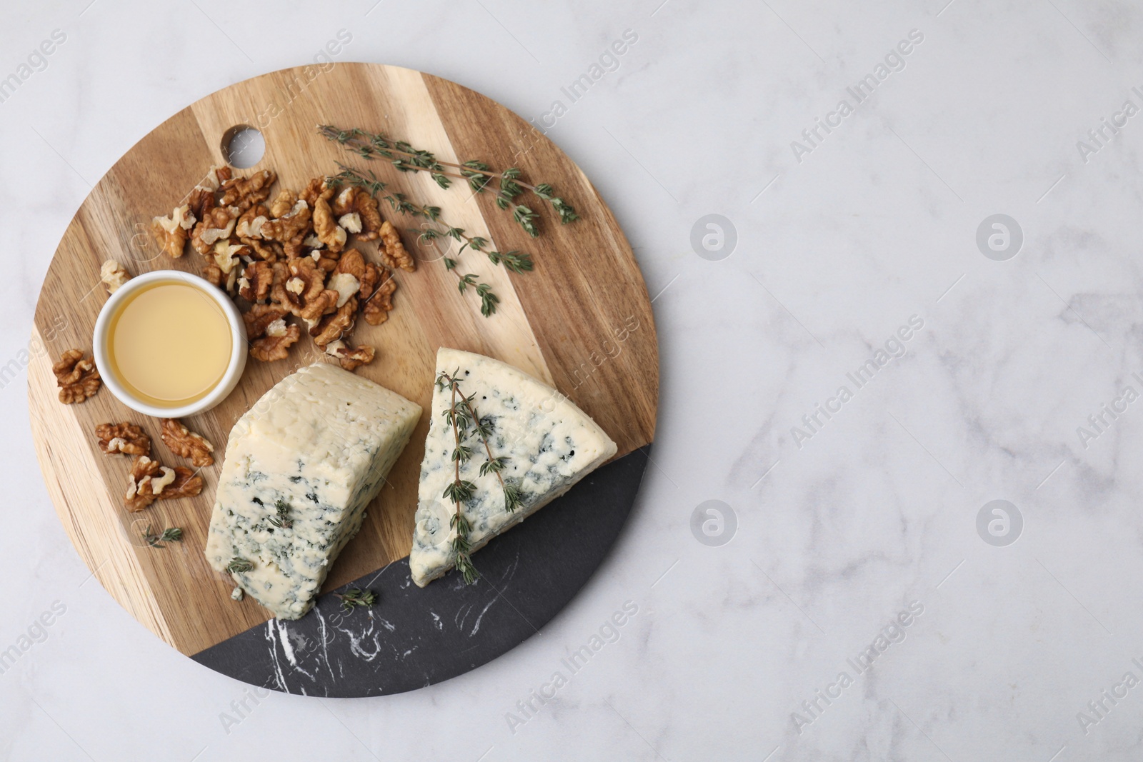 Photo of Tasty blue cheese with thyme, honey and walnuts on white marble table, top view. Space for text