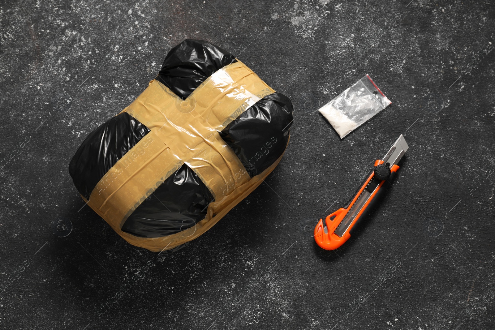 Photo of Packages with narcotics and stationery knife on black table, above view