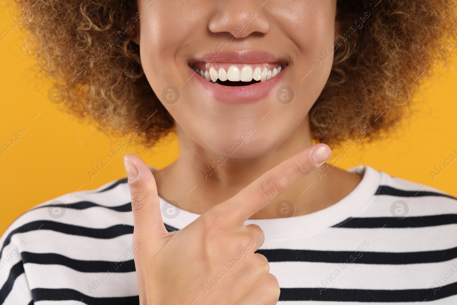 Photo of Woman showing her clean teeth on yellow background, closeup