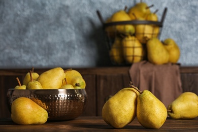 Photo of Fresh ripe pears on wooden table against blurred background