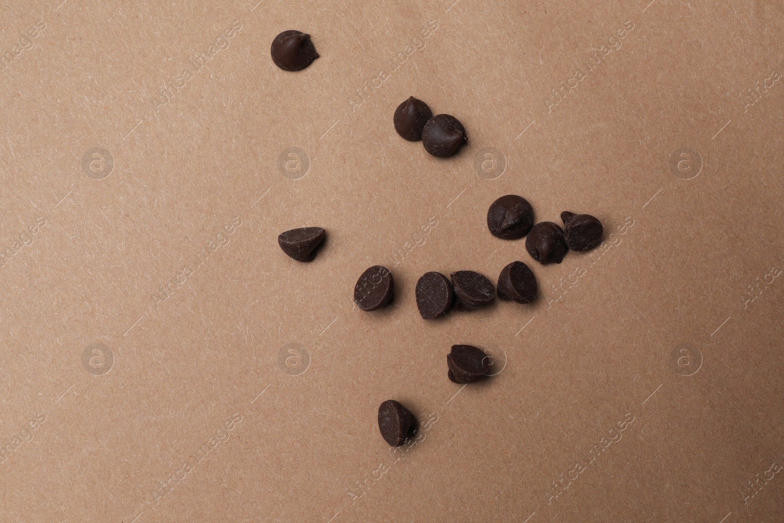 Photo of Delicious chocolate chips on brown background, top view