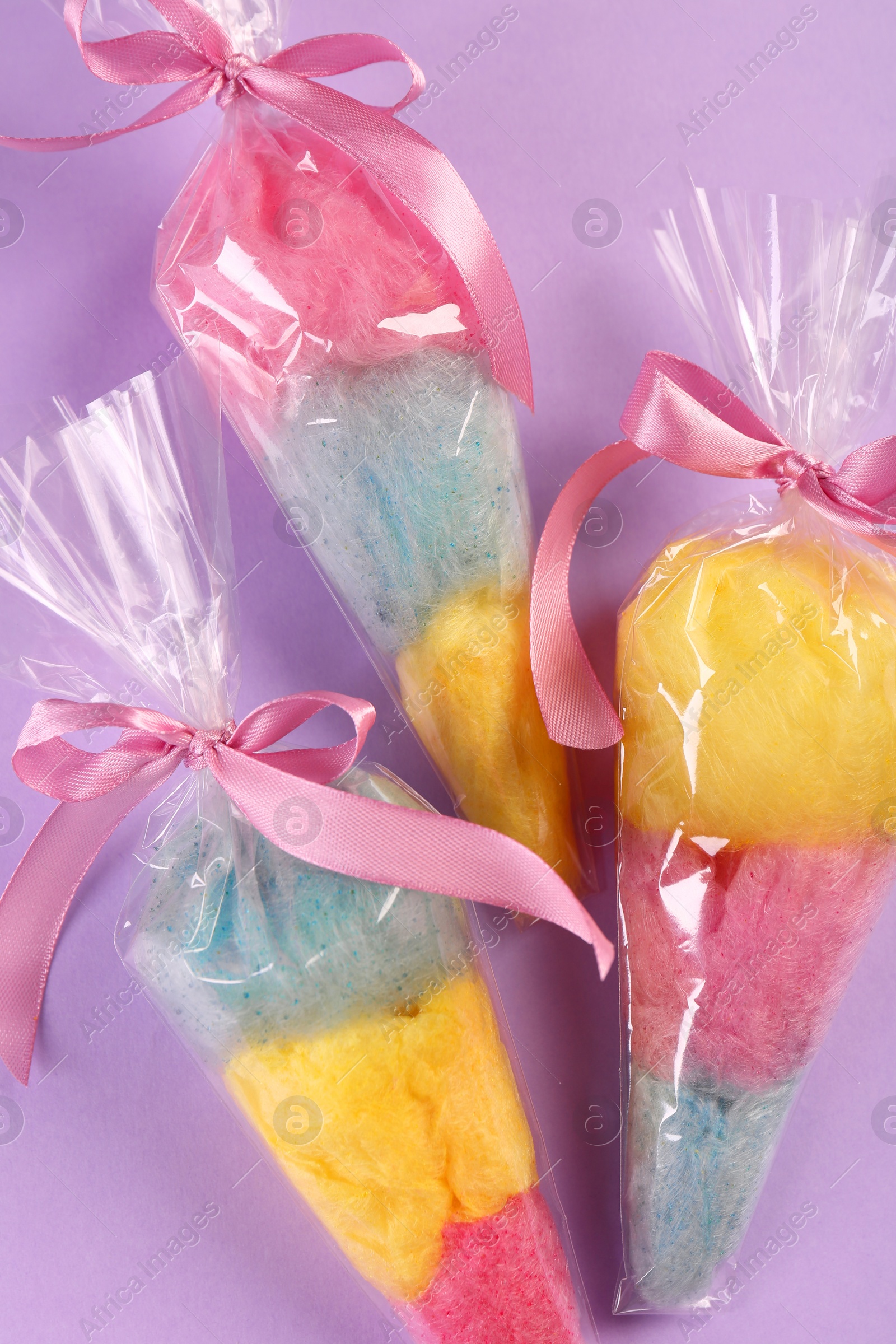 Photo of Packaged sweet cotton candies on violet background, flat lay