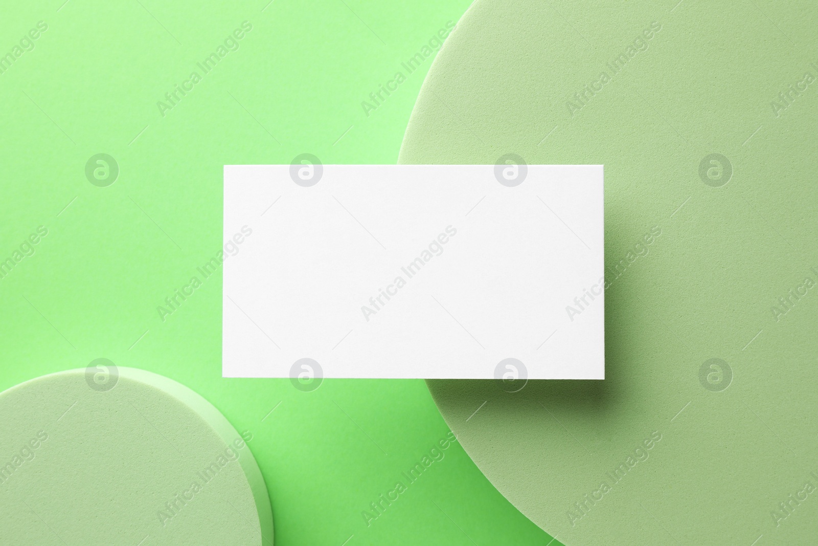 Photo of Empty business card and decorative elements on light green background, top view. Mockup for design