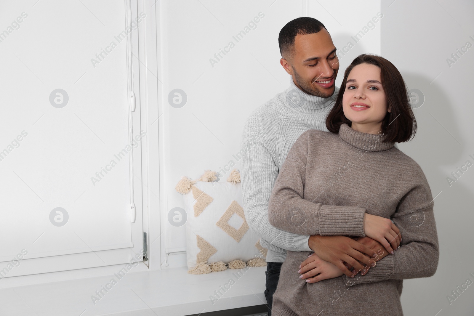 Photo of Dating agency. Couple hugging near window at home, space for text