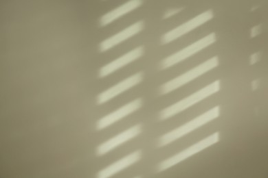 Photo of Light and shadow from window on beige wall indoors