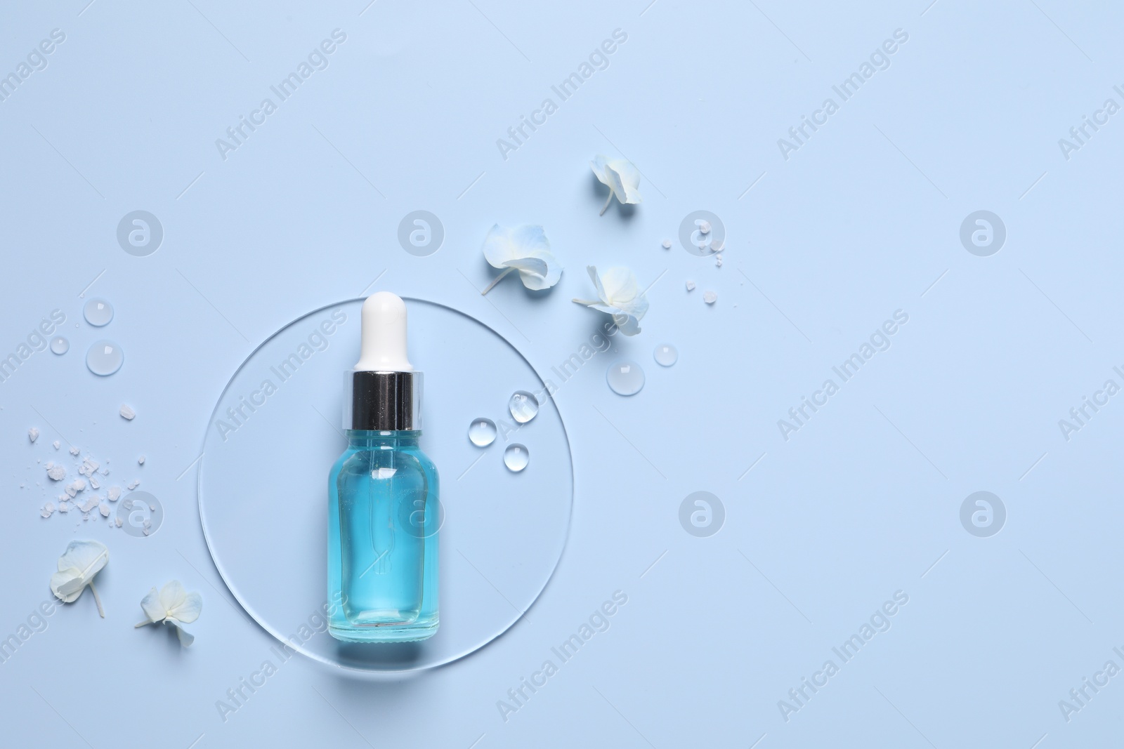 Photo of Bottle of cosmetic serum, flowers and sea salt on light blue background, flat lay. Space for text