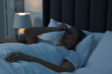 Photo of Woman suffering from headache in bed at night