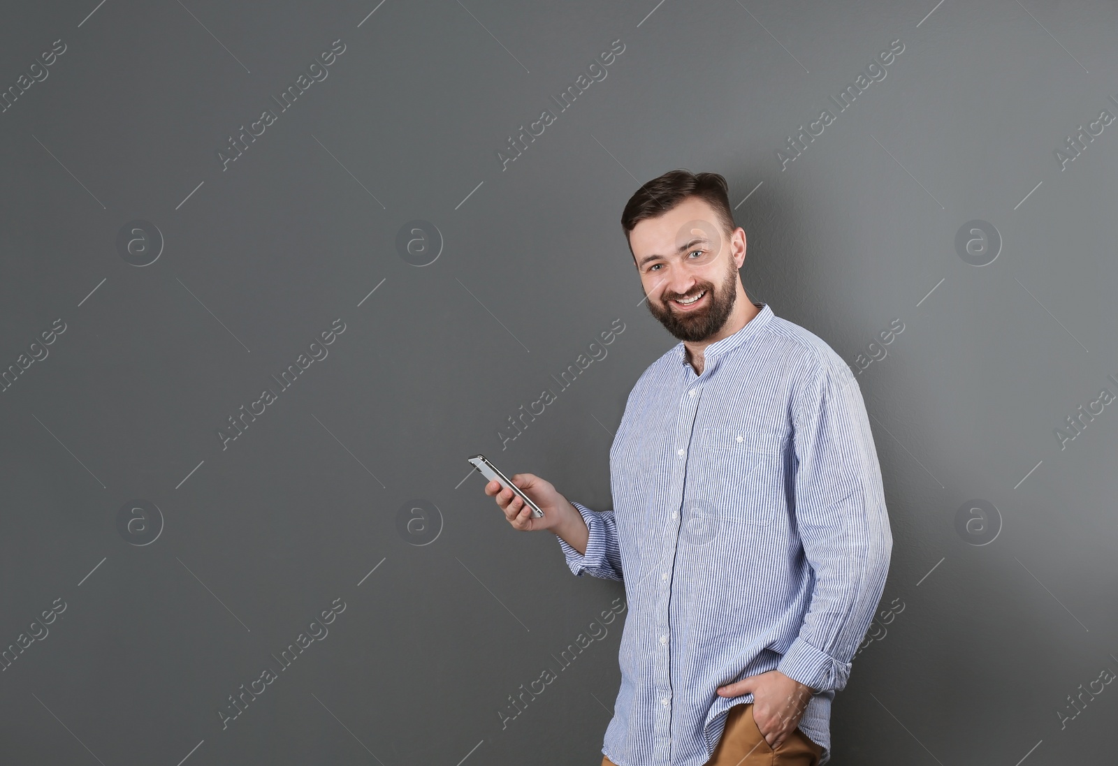 Photo of Portrait of handsome bearded man with mobile phone on color background
