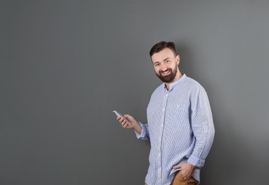 Portrait of handsome bearded man with mobile phone on color background