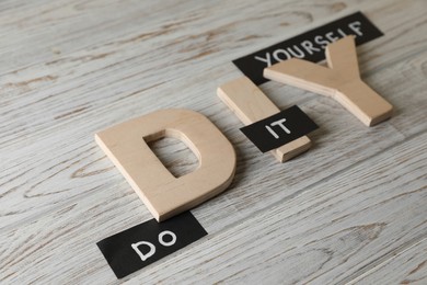 Photo of Phrase Do It Yourself and abbreviation DIY made of letters on white wooden table