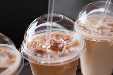 Photo of Plastic takeaway cups of delicious iced coffee with straws, closeup