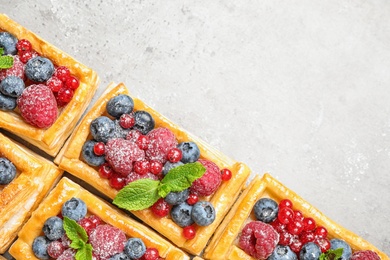 Fresh delicious puff pastry with sweet berries on grey background, flat lay. Space for text