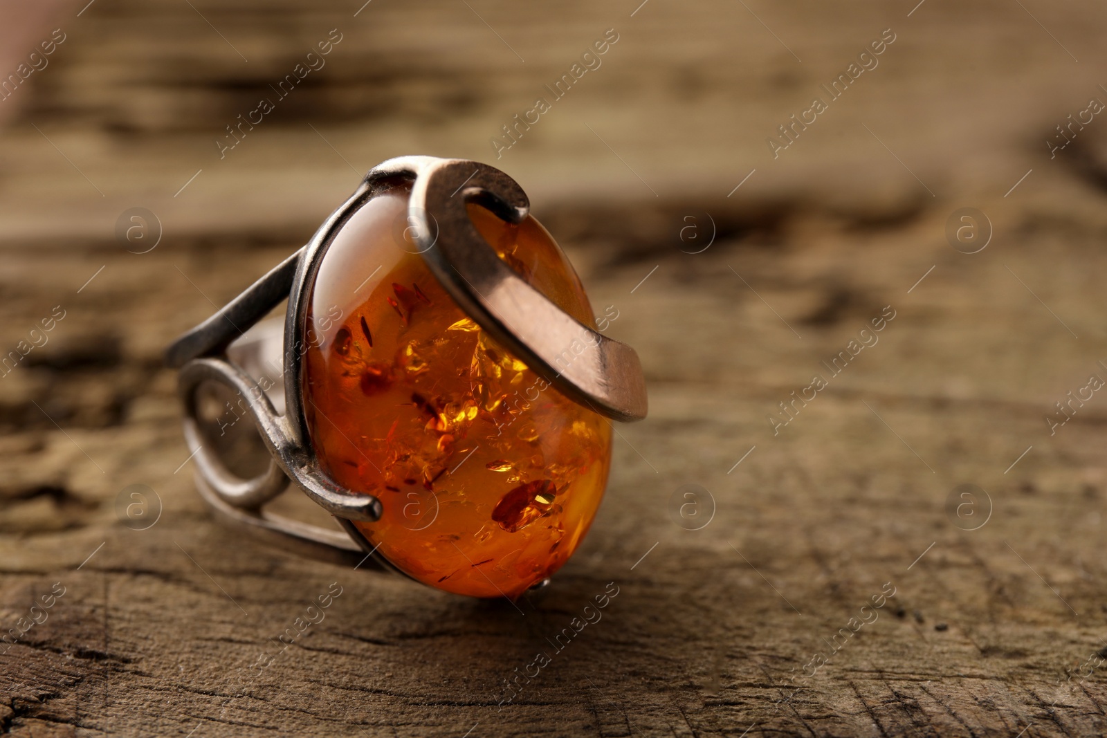 Photo of Beautiful ring with gemstone on wooden surface, closeup. Space for text