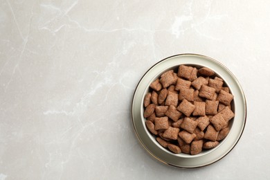 Sweet crispy corn pads in bowl on light marble table, top view. Space for text