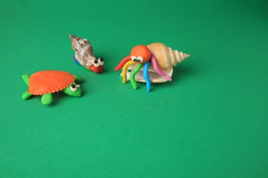 Turtle, crab and snail made from plasticine on green background, space for text. Children's handmade ideas