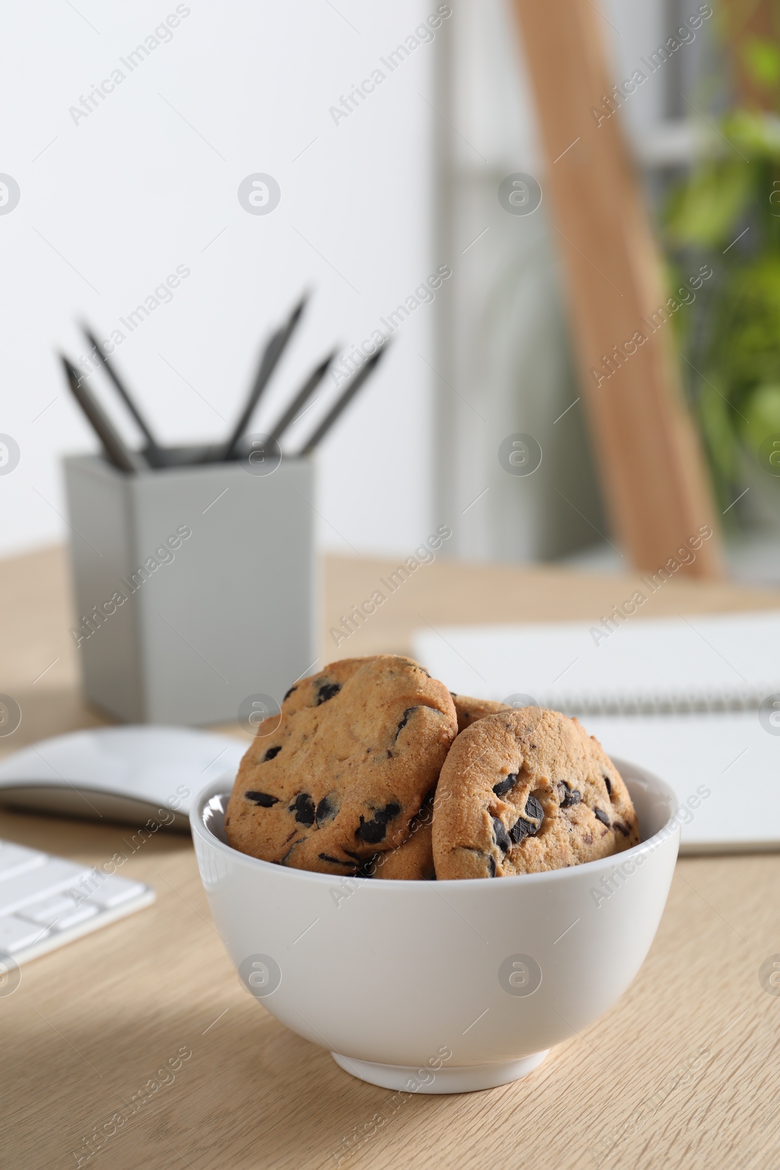 Photo of Chocolate chip cookies on wooden table at workplace