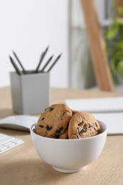 Photo of Chocolate chip cookies on wooden table at workplace