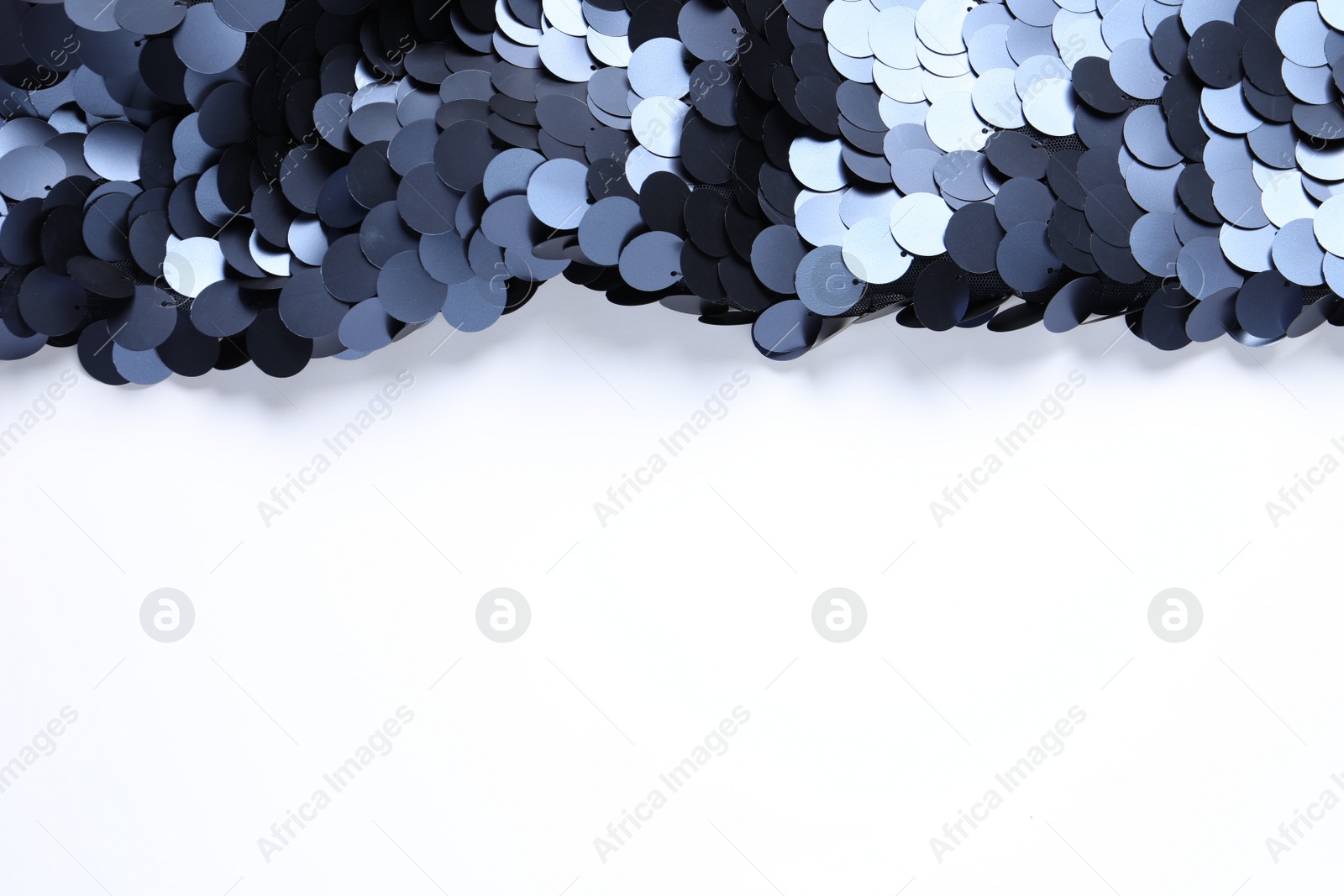 Photo of Beautiful shiny sequin fabric on white background, top view. Space for text