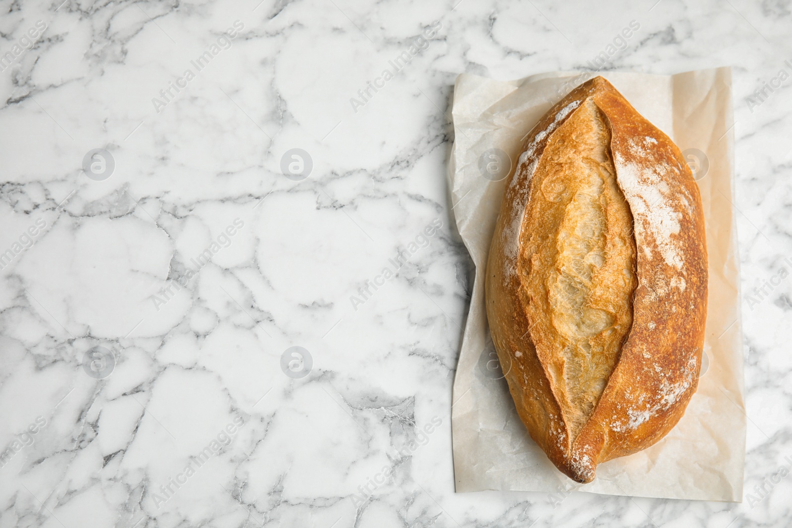 Photo of Loaf of fresh bread on white marble background, top view. Space for text