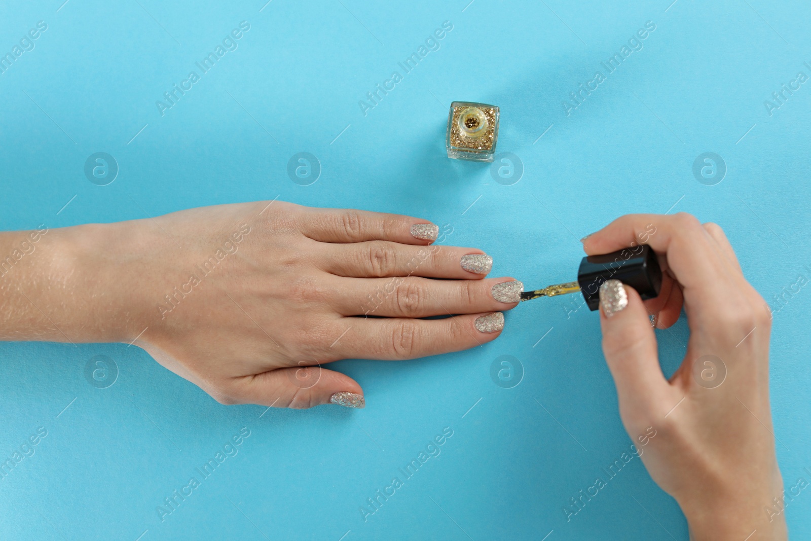 Photo of Woman applying nail polish on color background, top view