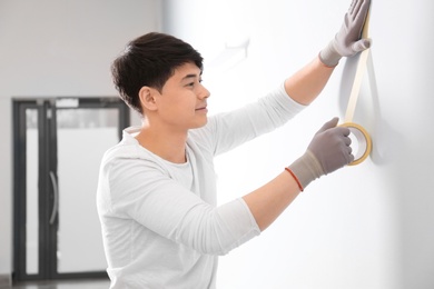Photo of Male decorator working with tape indoors