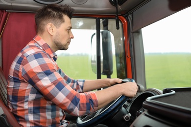 Professional driver sitting in cab of modern truck