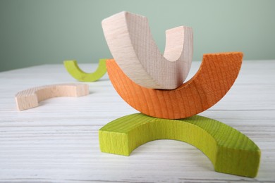 Photo of Colorful wooden pieces of educational toy on light table, closeup and space for text. Motor skills development