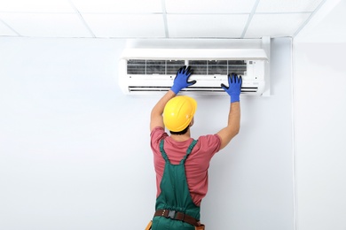 Photo of Male technician checking air conditioner indoors