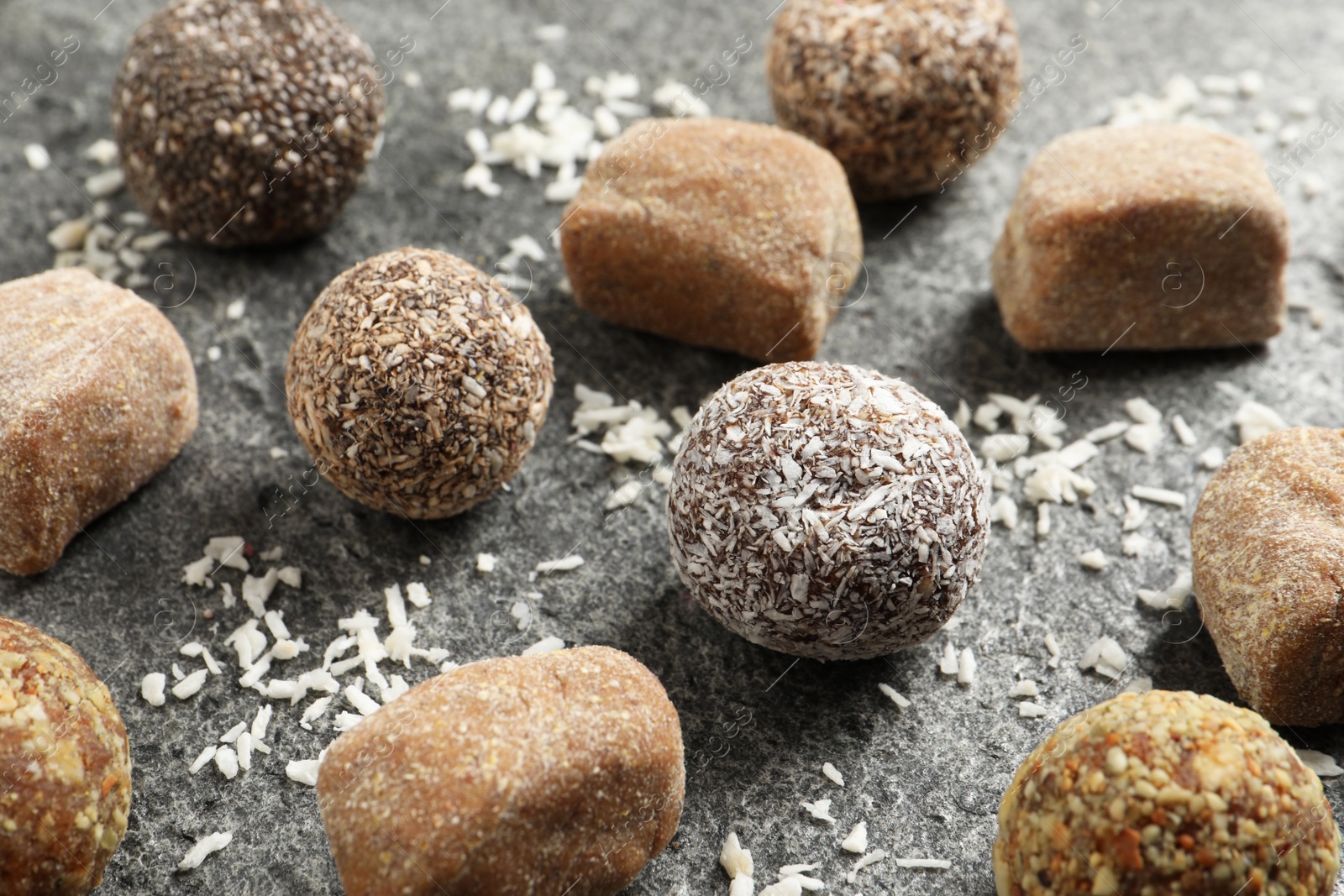 Photo of Different delicious vegan candy balls and desiccated coconut on grey table