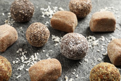 Photo of Different delicious vegan candy balls and desiccated coconut on grey table