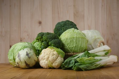 Photo of Many different types of fresh cabbage on wooden table