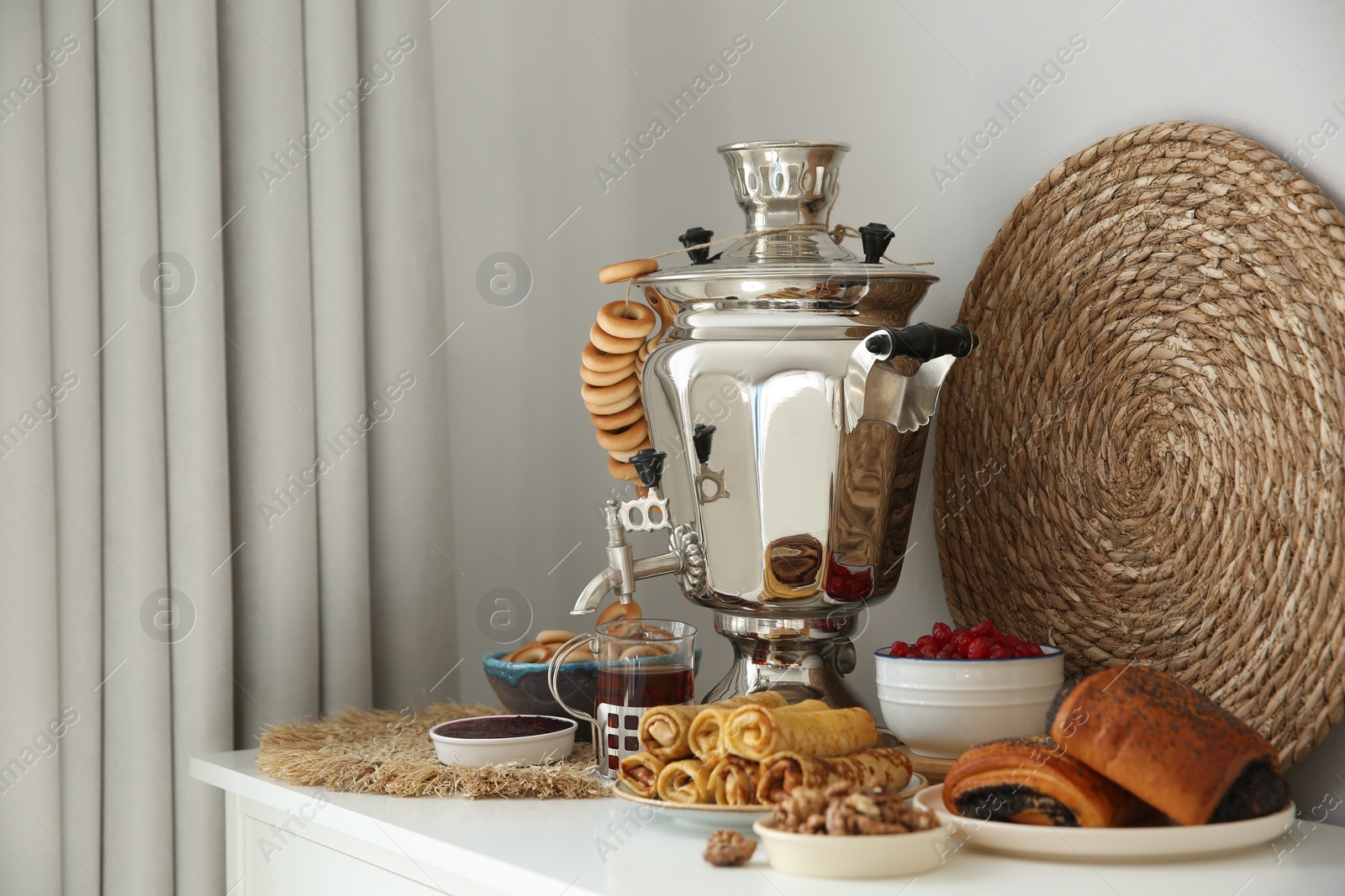 Photo of Traditional Russian samovar with treats on white table at home. Space for text